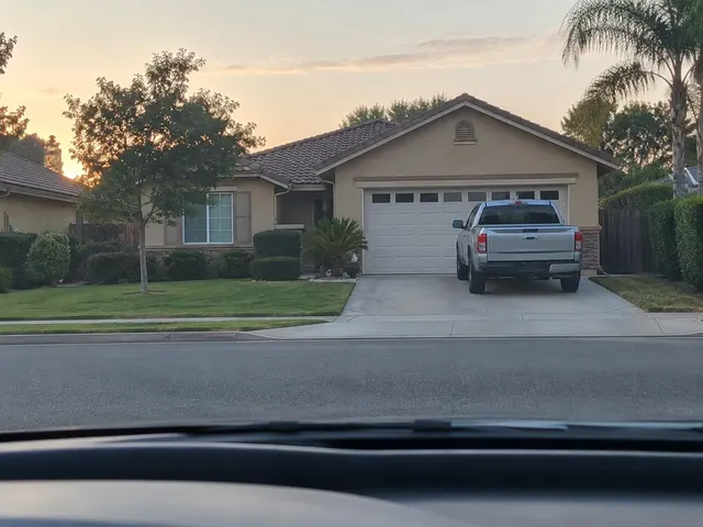 Dawn view from a parked car of a house with a silver pickup on the driveway