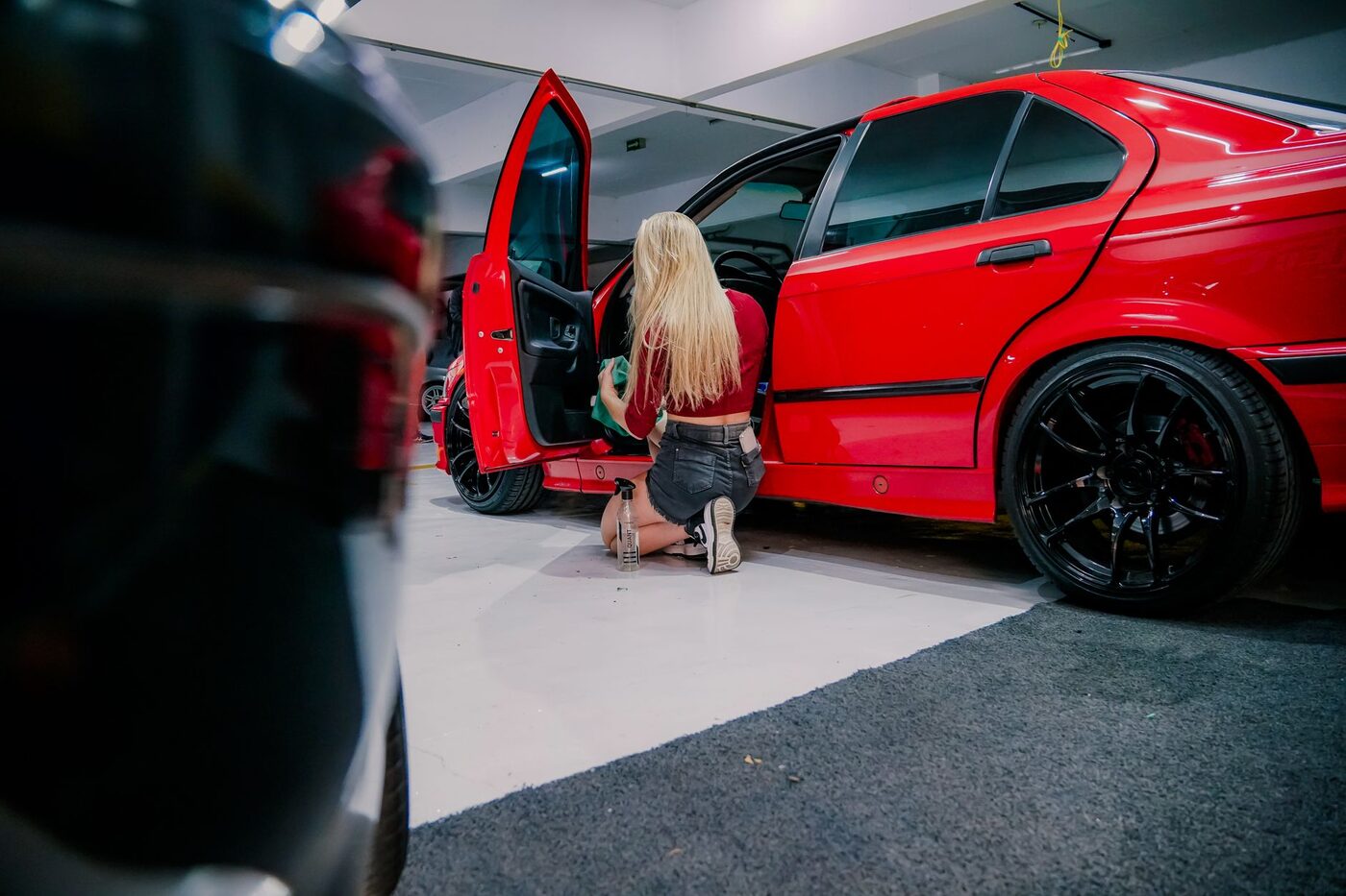 A person cleaning the interior of a red car in a garage