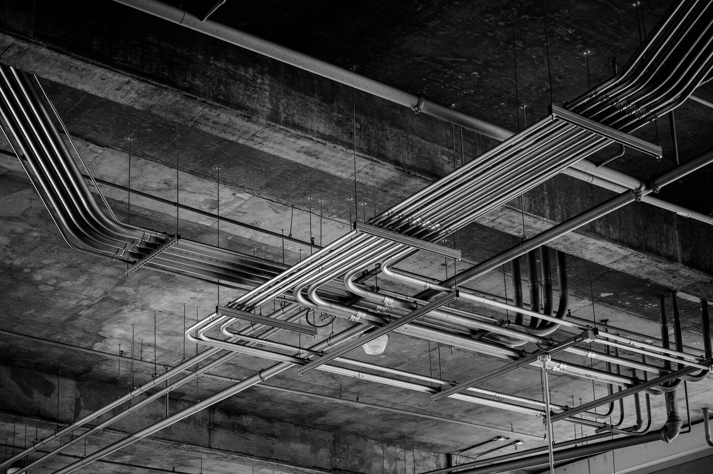 Parallel runs of electrical conduit with offset bends under a concrete ceiling