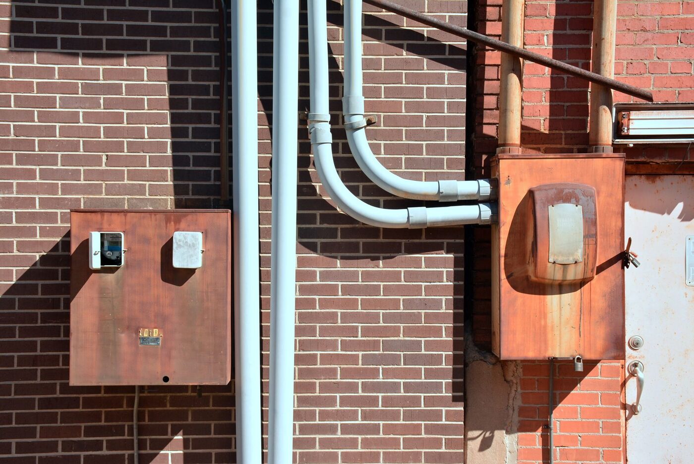 Metal conduit runs and outdoor enclosures mounted on a brick building wall