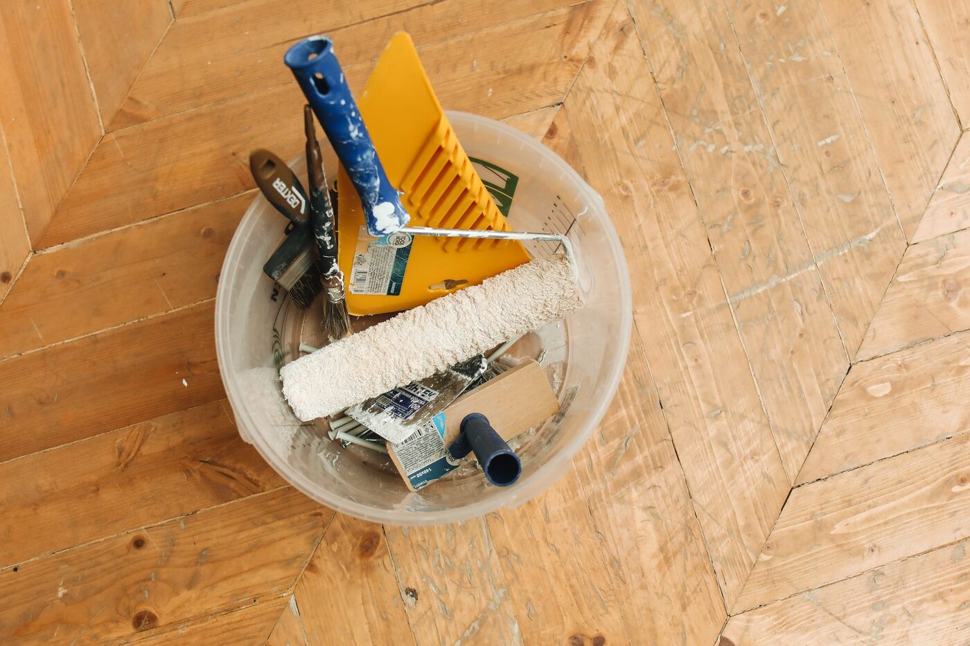 Paint tray with a roller and brush on a bare floor