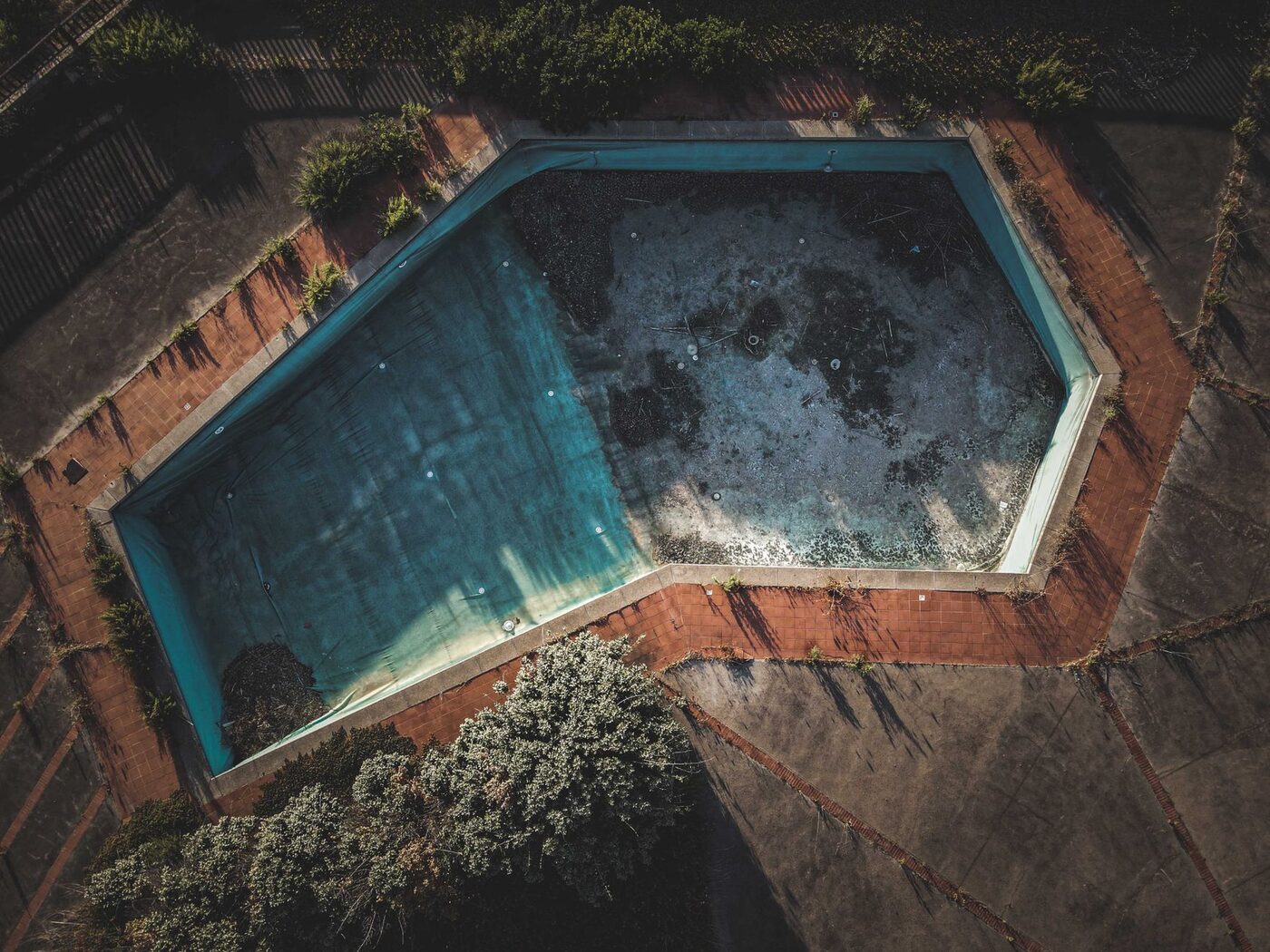 Aerial view of a neglected swimming pool with murky untreated water