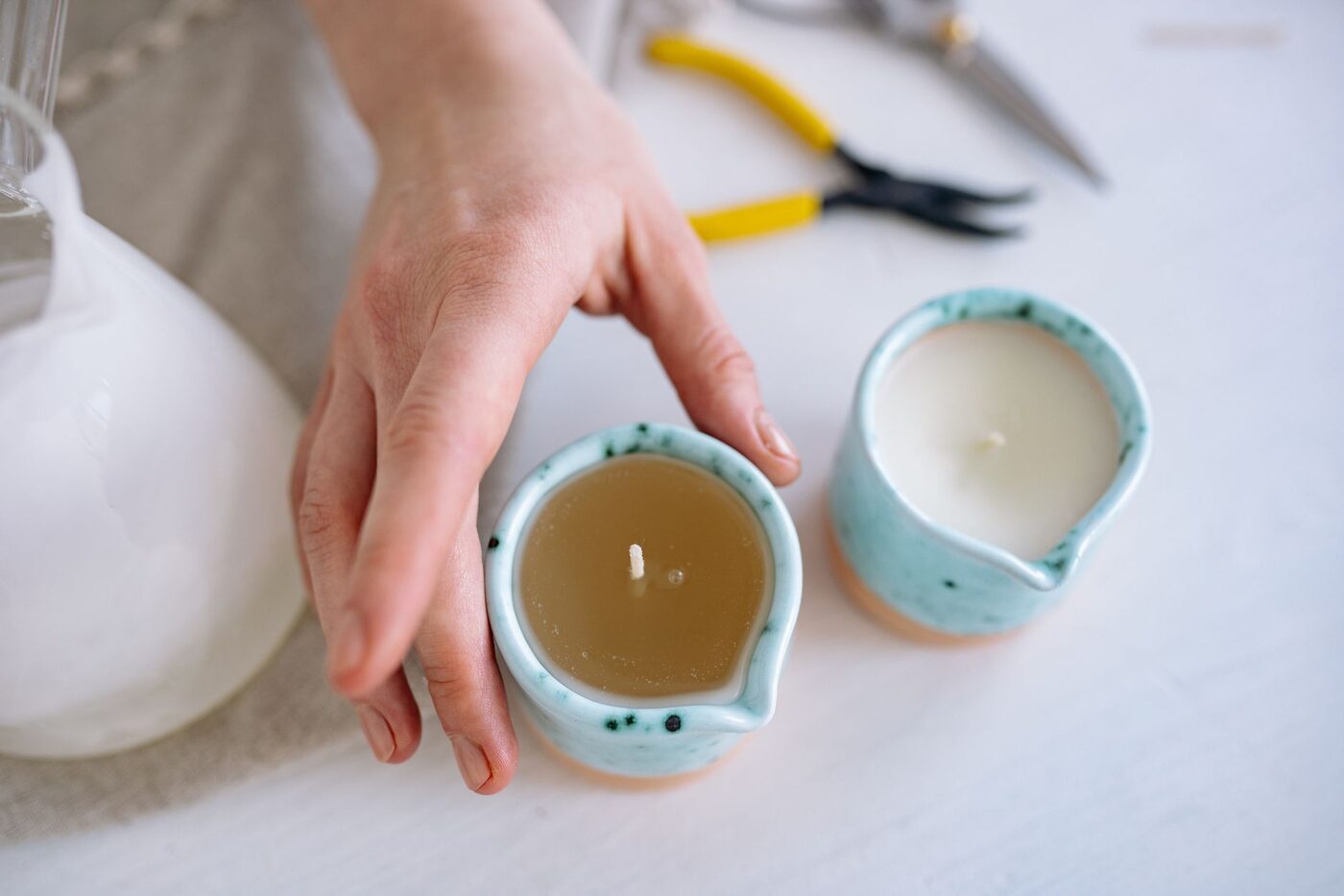 A maker handling a poured candle in a ceramic vessel