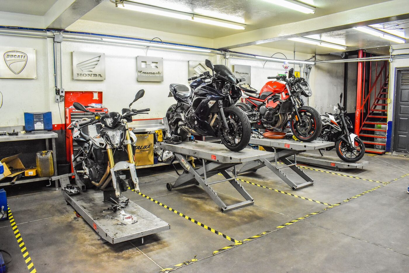 Several motorcycles on stands inside a workshop garage