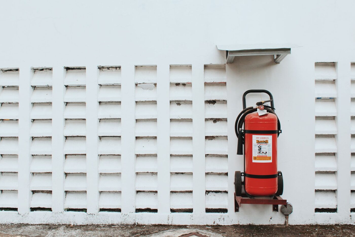 A red fire extinguisher mounted against a white wall