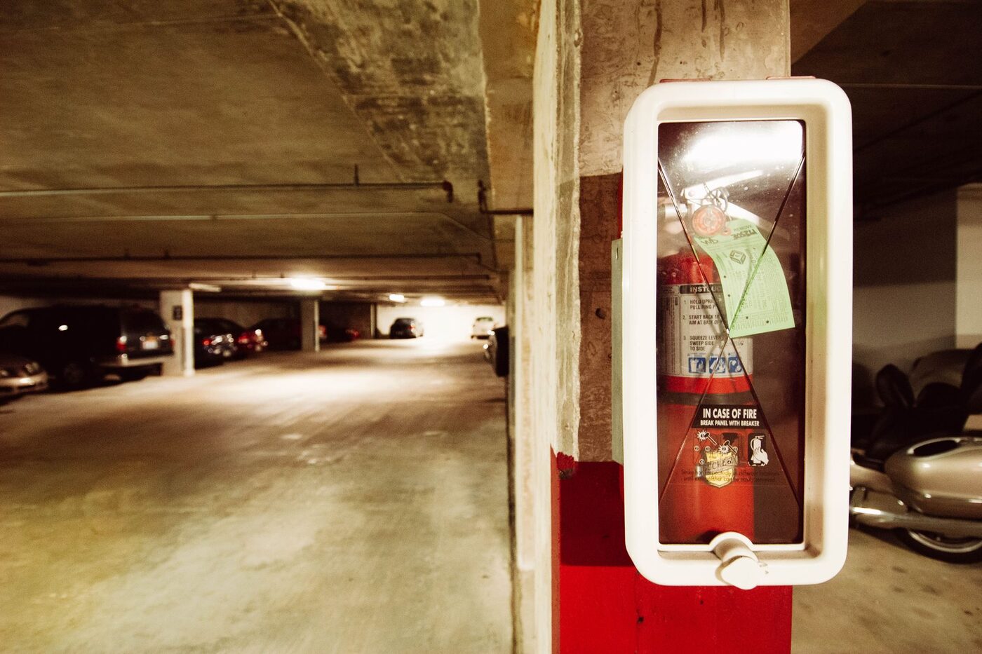 A fire extinguisher mounted in a concrete parking garage