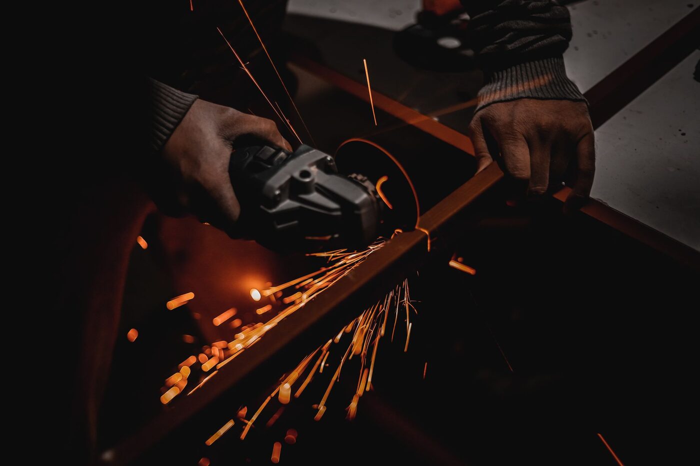 A worker using an angle grinder in a workshop, sparks flying