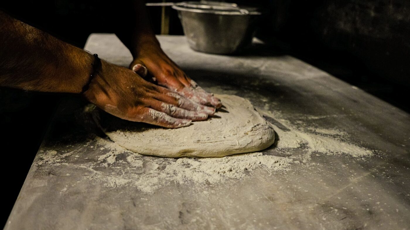 Hands working dough on a floured surface