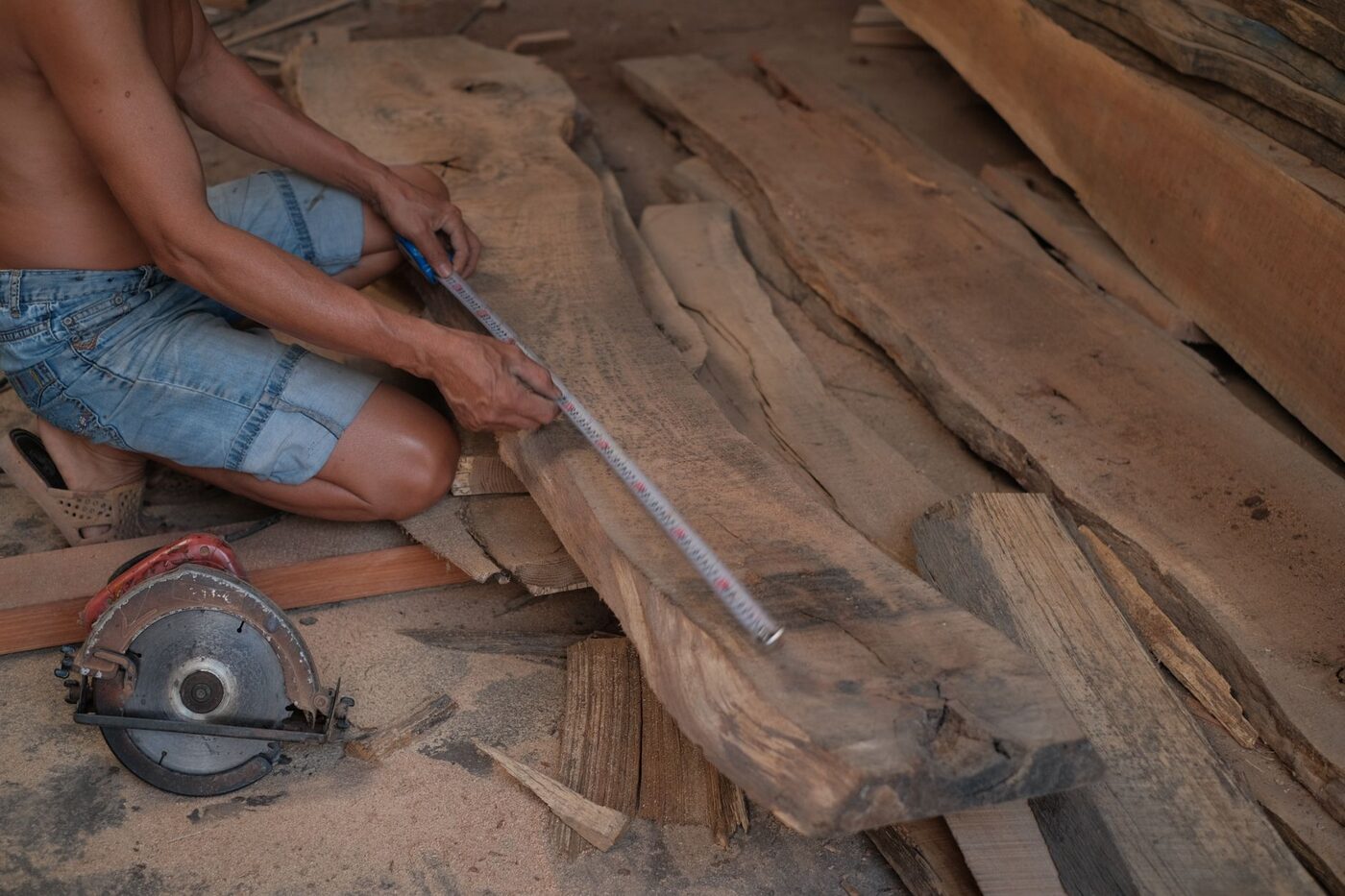 A carpenter measuring and marking a timber plank in a workshop